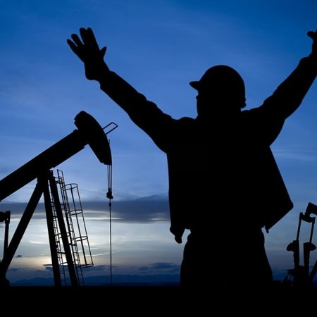 An Oil worker with his hands raised in the air in excitement.